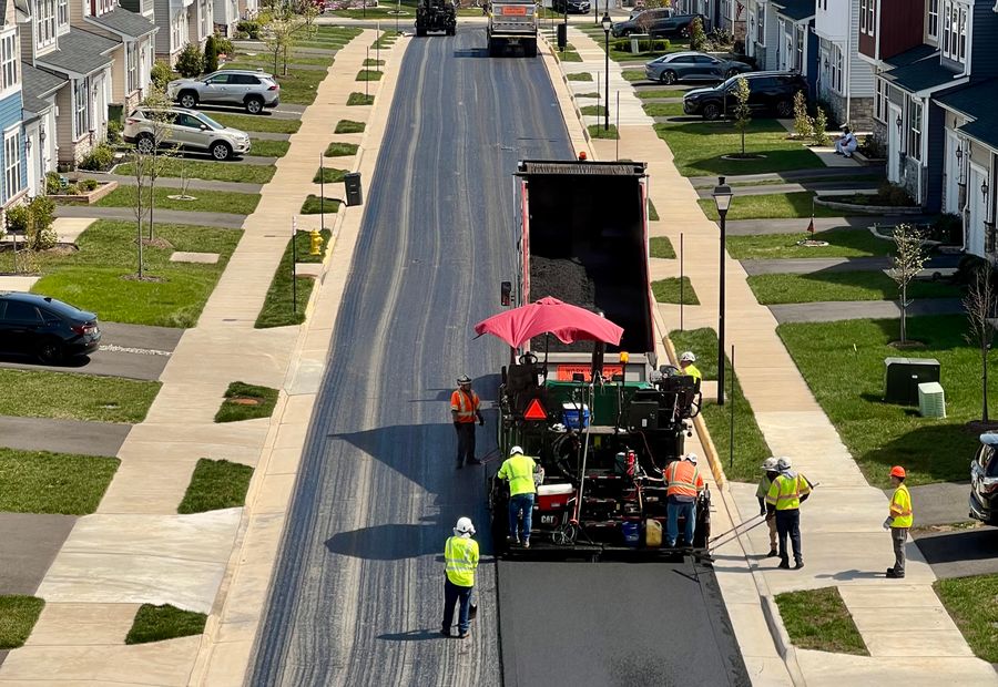 Paver laying a fresh mat of hot mix down a Rockford street while the crew works alongside it
