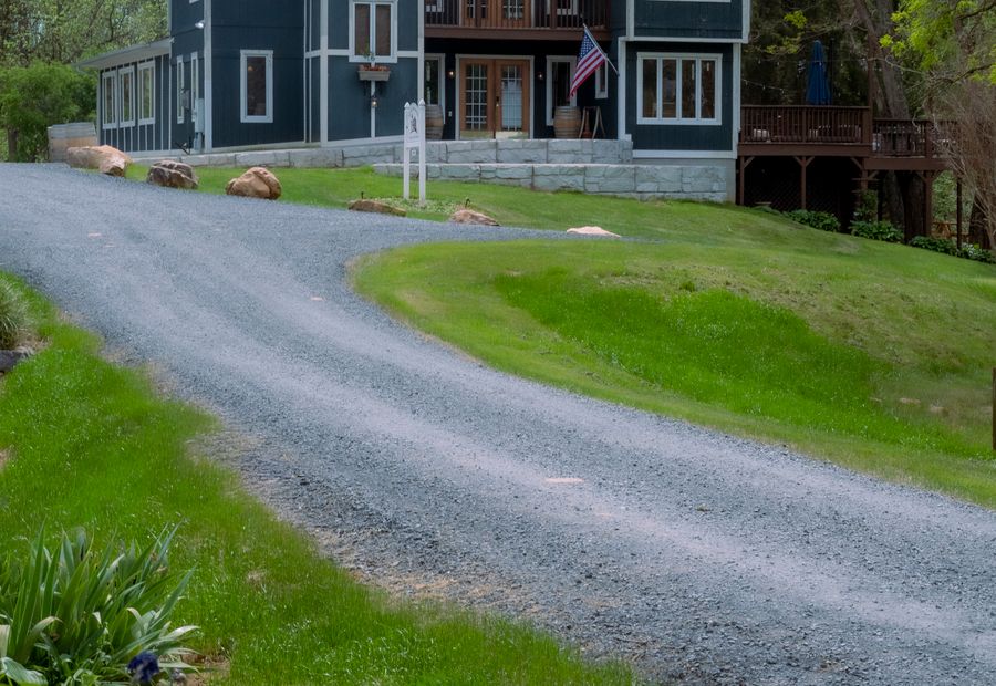 Gravel driveway curving through open ground toward a country house